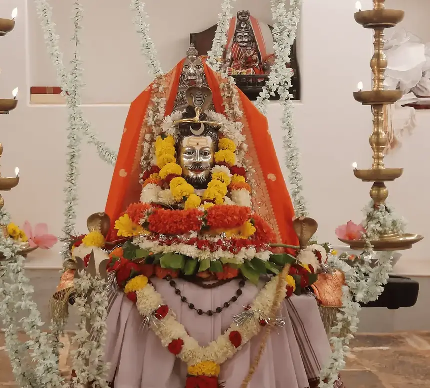 The Utsav Murti garlanded and flanked by samai lamps